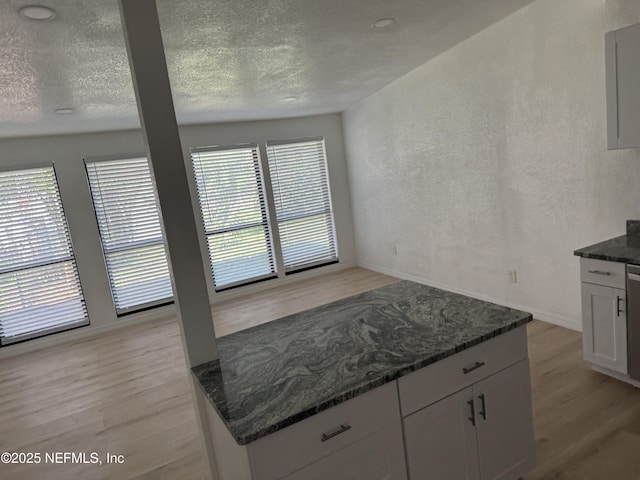 7942 Helston Dr, Jacksonville, FL 32208 - kitchen with light wood-style flooring, healthy amount of natural light, dark stone countertops, white cabinetry, and a textured ceiling