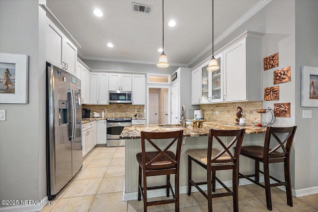 121 Bouganvilla Dr, Ponte Vedra Beach, FL 32082 - kitchen featuring appliances with stainless steel finishes, a peninsula, light stone counters, ornamental molding, and tasteful backsplash