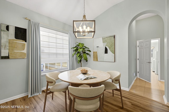 8523 Hampton Landing Dr, Jacksonville, FL 32256 - dining area featuring arched walkways, wood finished floors, lofted ceiling, and a chandelier