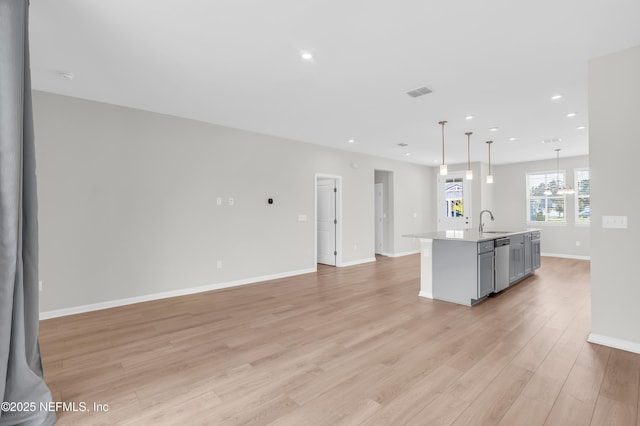 575 Buttonwood Loop, Yulee, FL 32097 - kitchen with dishwasher, light countertops, a center island with sink, light wood-style floors, and pendant lighting