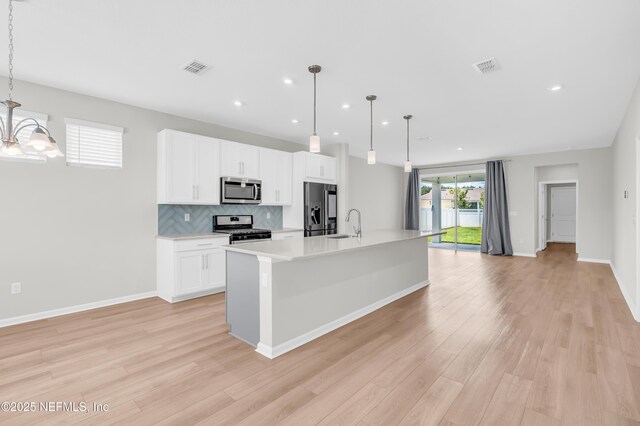 575 Buttonwood Loop, Yulee, FL 32097 - kitchen with stainless steel appliances, light wood finished floors, light countertops, a kitchen island with sink, and recessed lighting