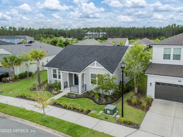575 Buttonwood Loop, Yulee, FL 32097 - view of front facade with a shingled roof, a porch, a front yard, board and batten siding, and driveway