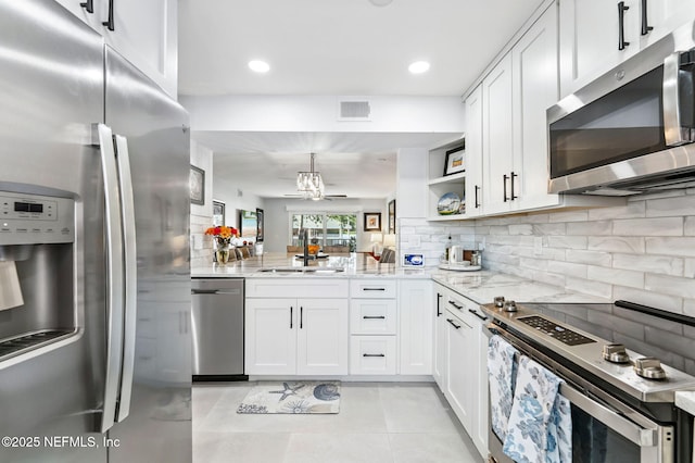 212 16th St Unit A, Saint Augustine Beach, FL 32080 - kitchen with stainless steel appliances, light stone countertops, white cabinetry, decorative backsplash, and light tile patterned floors
