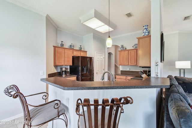 12569 Kernan Forest Blvd, Jacksonville, FL 32225 - kitchen featuring black fridge with ice dispenser, dark countertops, a peninsula, a breakfast bar area, and crown molding
