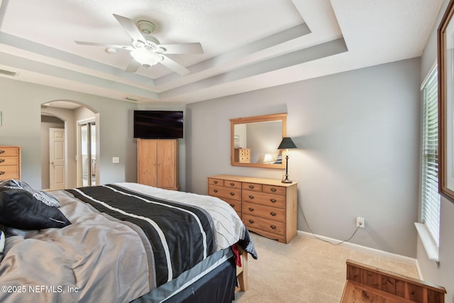 12569 Kernan Forest Blvd, Jacksonville, FL 32225 - bedroom with a tray ceiling, arched walkways, light carpet, and a ceiling fan