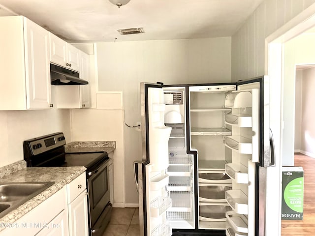 8953 Adams Ave, Jacksonville, FL 32208 - kitchen with stainless steel electric stove, refrigerator, under cabinet range hood, and white cabinetry