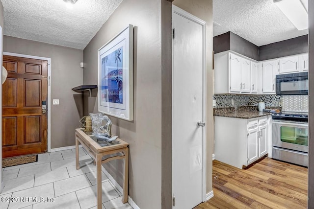 2120 Derringer Cir W, Jacksonville, FL 32225 - kitchen with electric stove, black microwave, a textured ceiling, white cabinetry, and tasteful backsplash