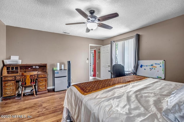2120 Derringer Cir W, Jacksonville, FL 32225 - bedroom with light wood-type flooring, a textured ceiling, freestanding refrigerator, and ceiling fan