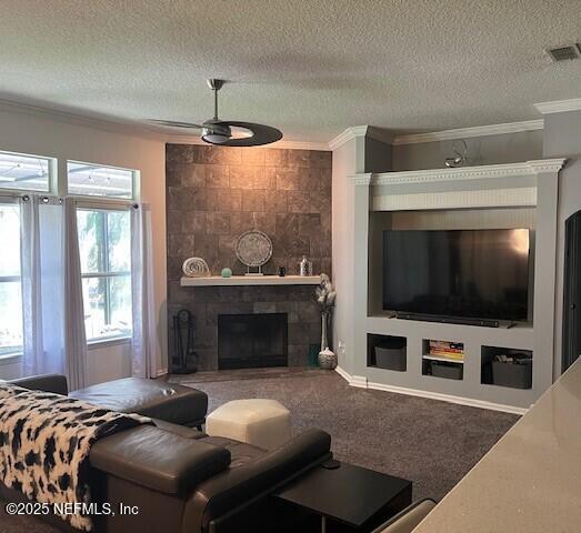 2506 Willow Creek Dr, Fleming Island, FL 32003 - living area featuring crown molding, plenty of natural light, a ceiling fan, a tiled fireplace, and a textured ceiling