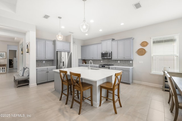 147 Rawlings Dr, Saint Johns, FL 32259 - kitchen with gray cabinetry, appliances with stainless steel finishes, backsplash, a breakfast bar area, and light countertops