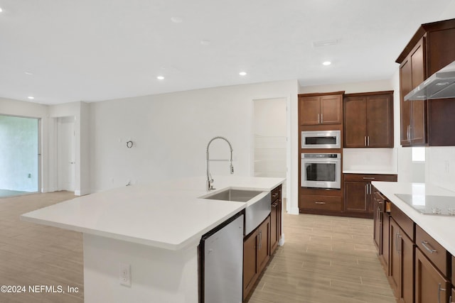 3245 Pipers Way, Green Cove Springs, FL 32043 - kitchen with appliances with stainless steel finishes, wall chimney exhaust hood, light wood finished floors, light countertops, and a kitchen island with sink