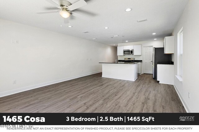 1001 Aiken St, Saint Augustine, FL 32084 - kitchen with stainless steel appliances, dark countertops, recessed lighting, wood finished floors, and white cabinets