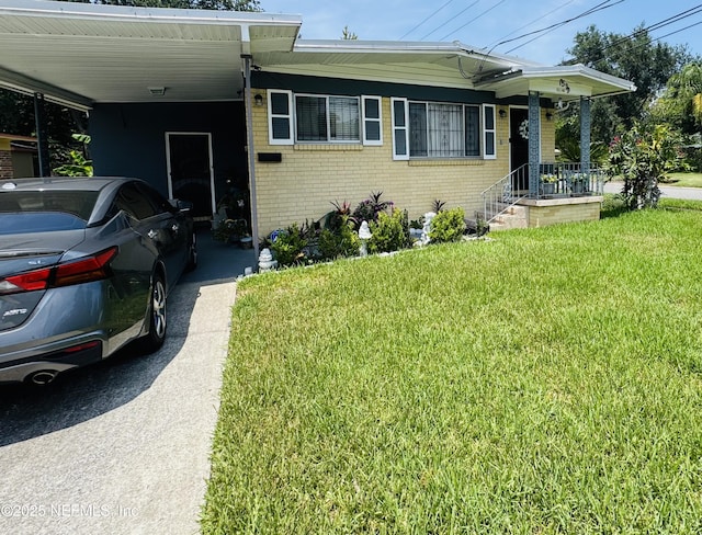 2529 W 28th St, Jacksonville, FL 32209 - view of front of home with brick siding, a carport, a front yard, and driveway