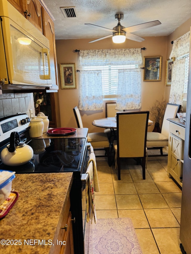 2529 W 28th St, Jacksonville, FL 32209 - kitchen with stainless steel electric range oven, white microwave, a textured ceiling, ceiling fan, and brown cabinetry
