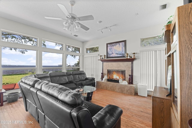 3305 US Highway 17, Fleming Island, FL 32003 - living area featuring a tiled fireplace, rail lighting, light wood-type flooring, a textured ceiling, and ceiling fan