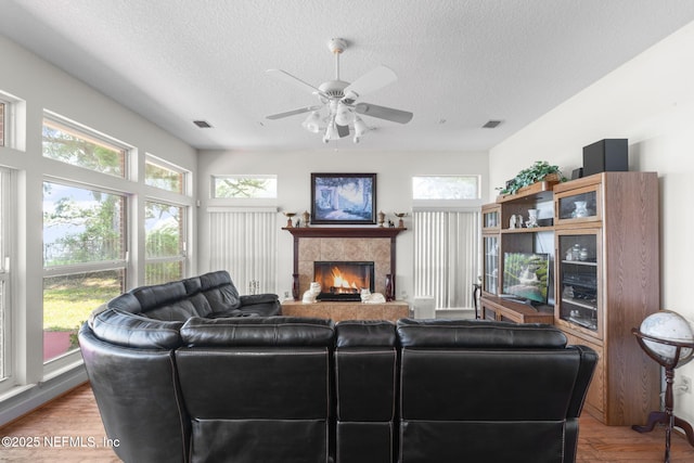 3305 US Highway 17, Fleming Island, FL 32003 - living room featuring plenty of natural light, a textured ceiling, a tile fireplace, a ceiling fan, and light wood-style flooring