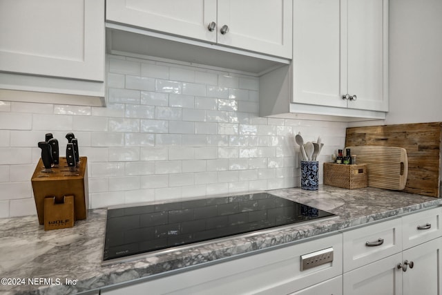 105 Teal Nest Ct, Ponte Vedra Beach, FL 32082 - kitchen with black electric stovetop, backsplash, white cabinets, and light stone counters