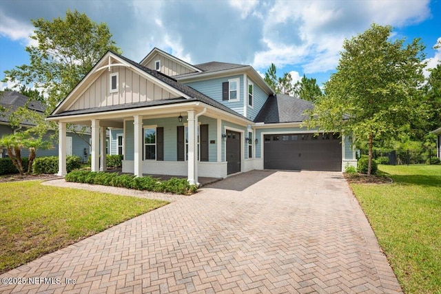 305 Seahill Dr, Saint Augustine, FL 32092 - view of front facade with board and batten siding, decorative driveway, a garage, a front yard, and a porch