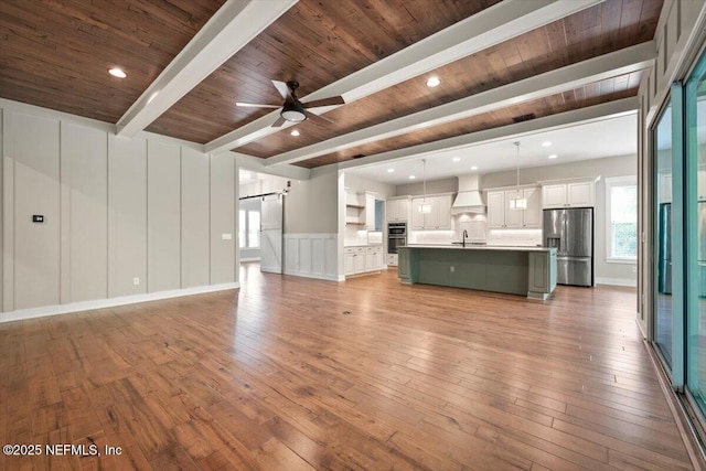 305 Seahill Dr, Saint Augustine, FL 32092 - unfurnished living room featuring a barn door, a decorative wall, hardwood / wood-style floors, ceiling fan, and a wood ceiling with exposed beams