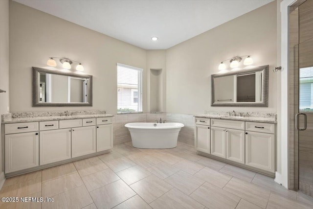 305 Seahill Dr, Saint Augustine, FL 32092 - full bathroom featuring tile walls, two vanities, a freestanding tub, a shower stall, and a wainscoted wall