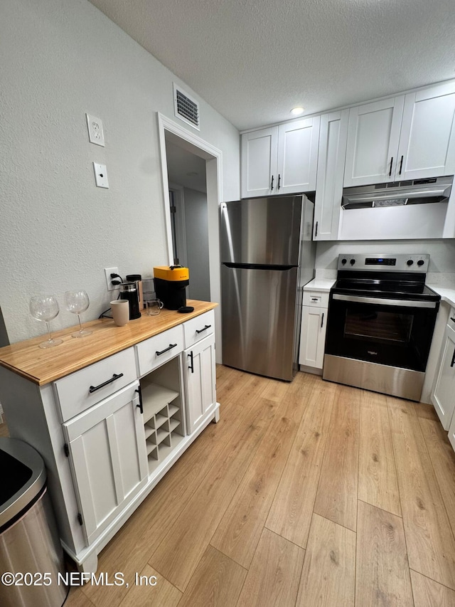 1618 El Camino Rd Unit 2, Jacksonville, FL 32216 - kitchen with stainless steel appliances, under cabinet range hood, white cabinetry, light wood-type flooring, and a textured ceiling