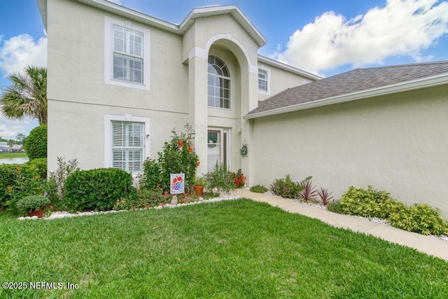 76146 Long Leaf Loop, Yulee, FL 32097 - view of front of home featuring stucco siding, a front yard, and roof with shingles