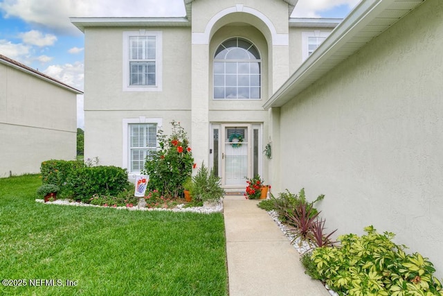 76146 Long Leaf Loop, Yulee, FL 32097 - view of exterior entry featuring stucco siding and a lawn