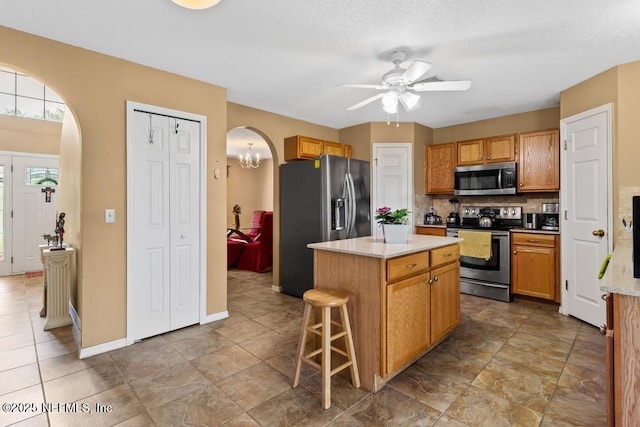76146 Long Leaf Loop, Yulee, FL 32097 - kitchen featuring stainless steel appliances, arched walkways, ceiling fan, a center island, and backsplash