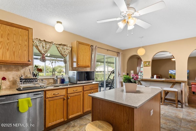 76146 Long Leaf Loop, Yulee, FL 32097 - kitchen with stainless steel appliances, tasteful backsplash, ceiling fan, brown cabinets, and a center island