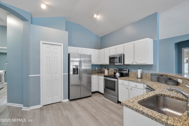 253 Bell Branch Ln, Saint Johns, FL 32259 - kitchen with stainless steel appliances, arched walkways, light stone counters, white cabinets, and high vaulted ceiling