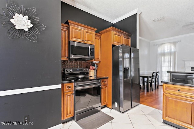 9540 Broken Oak Blvd, Jacksonville, FL 32257 - kitchen featuring appliances with stainless steel finishes, crown molding, dark countertops, light tile patterned floors, and brown cabinetry