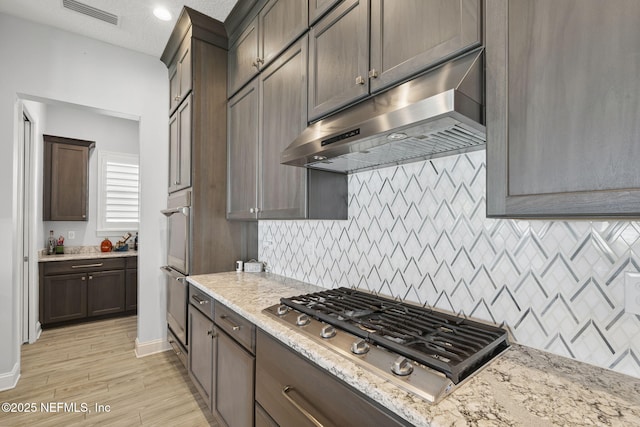 50 Tartan Ct, Saint Augustine, FL 32092 - kitchen featuring appliances with stainless steel finishes, under cabinet range hood, light stone counters, backsplash, and light wood finished floors