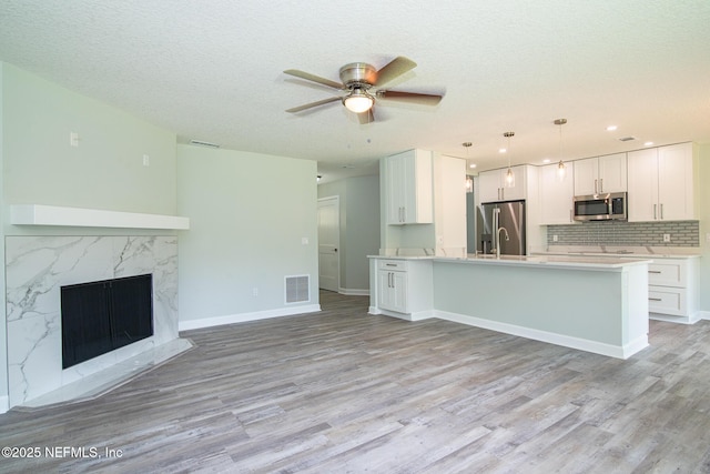 7038 Holiday Hill Ct, Jacksonville, FL 32216 - kitchen with stainless steel appliances, open floor plan, ceiling fan, light wood-style flooring, and white cabinetry
