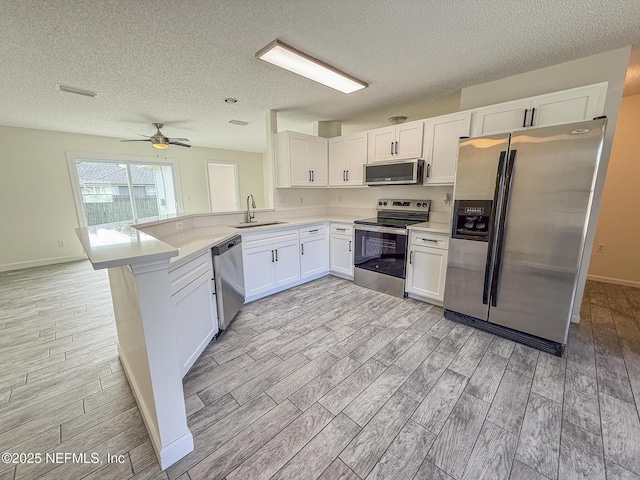 1736 Ashwood Cir, Middleburg, FL 32068 - kitchen featuring appliances with stainless steel finishes, wood finish floors, a peninsula, light countertops, and a textured ceiling