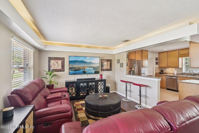 6405 Simca Dr, Jacksonville, FL 32277 - living room with a textured ceiling, a raised ceiling, and light wood-style floors