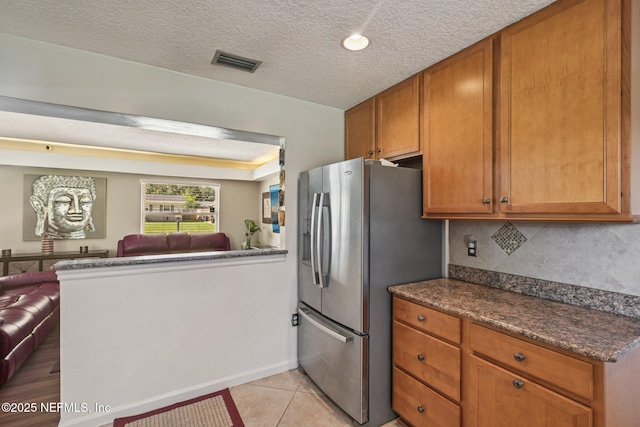 6405 Simca Dr, Jacksonville, FL 32277 - kitchen featuring open floor plan, stainless steel fridge with ice dispenser, tasteful backsplash, a peninsula, and brown cabinetry