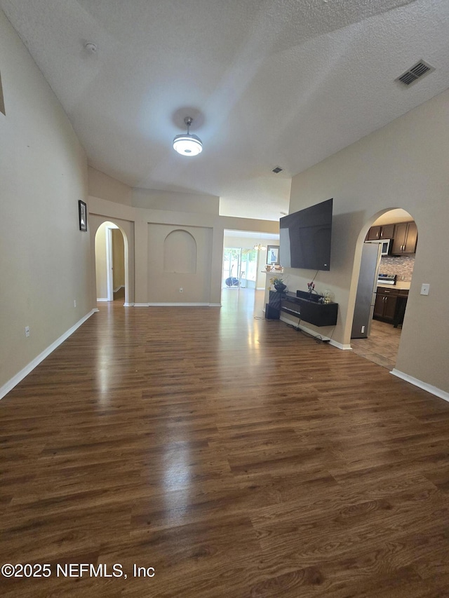 3472 Steelgate Ct, Middleburg, FL 32068 - unfurnished living room featuring arched walkways, dark wood-style flooring, and a textured ceiling