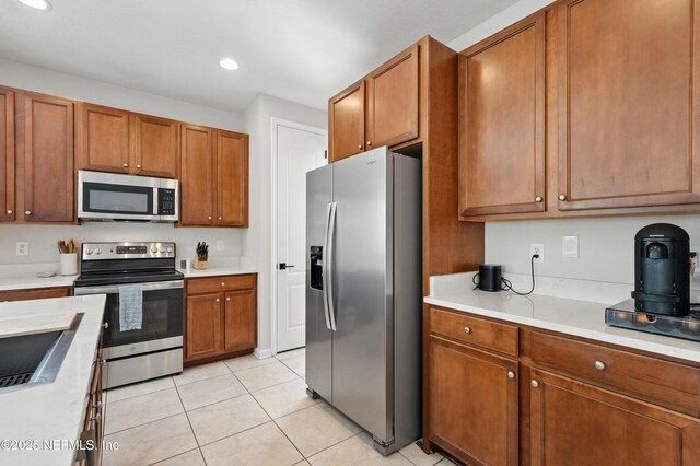 12191 Wynnfield Lakes Cir, Jacksonville, FL 32246 - kitchen featuring appliances with stainless steel finishes, light countertops, brown cabinetry, light tile patterned flooring, and recessed lighting