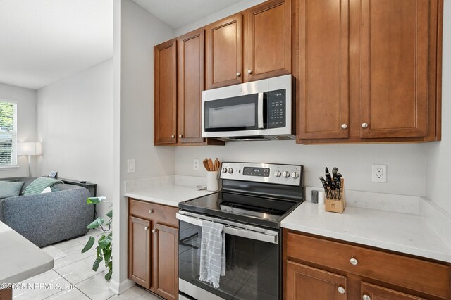 12191 Wynnfield Lakes Cir, Jacksonville, FL 32246 - kitchen with stainless steel appliances, open floor plan, light countertops, and brown cabinetry