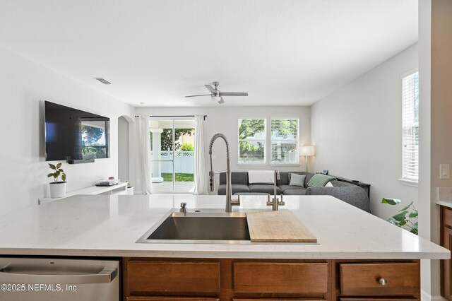 12191 Wynnfield Lakes Cir, Jacksonville, FL 32246 - kitchen featuring stainless steel dishwasher, open floor plan, ceiling fan, brown cabinetry, and arched walkways