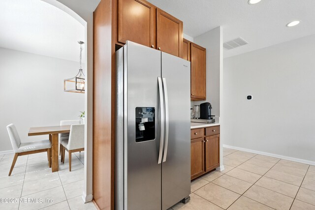 12191 Wynnfield Lakes Cir, Jacksonville, FL 32246 - kitchen with stainless steel fridge with ice dispenser, light tile patterned floors, brown cabinets, and recessed lighting