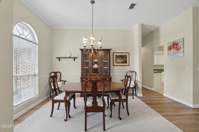 6992 Tonga Dr, Jacksonville, FL 32216 - dining space with healthy amount of natural light, light wood-style floors, a chandelier, and crown molding
