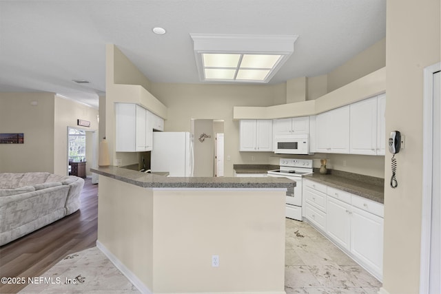 6992 Tonga Dr, Jacksonville, FL 32216 - kitchen featuring white appliances, dark countertops, a peninsula, and white cabinets