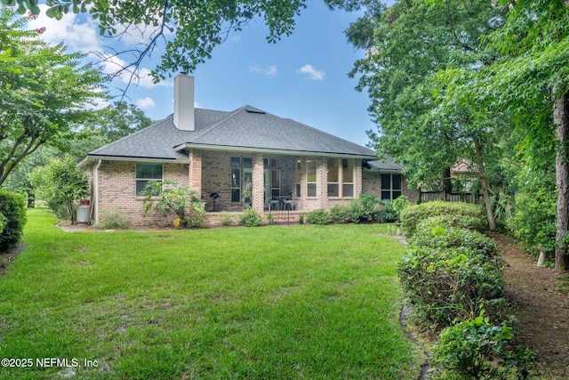 6992 Tonga Dr, Jacksonville, FL 32216 - back of house featuring brick siding, a yard, a chimney, and roof with shingles