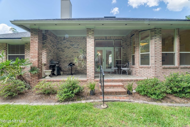 6992 Tonga Dr, Jacksonville, FL 32216 - doorway to property with brick siding, a chimney, french doors, and a patio