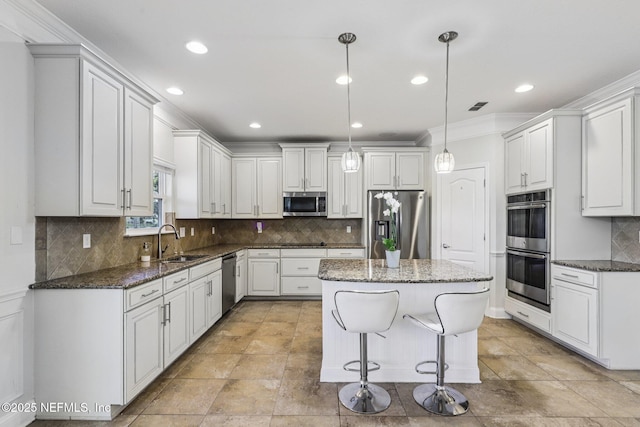 738 W Kings College Dr, Fruit Cove, FL 32259 - kitchen with appliances with stainless steel finishes, a kitchen island, dark stone countertops, backsplash, and ornamental molding