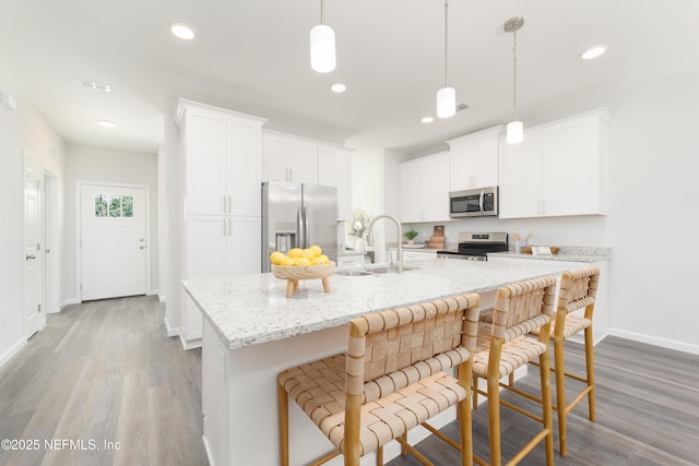 380 Jefferson Rd, Jacksonville, FL 32225 - kitchen featuring stainless steel appliances, wood finished floors, a kitchen island with sink, white cabinetry, and recessed lighting
