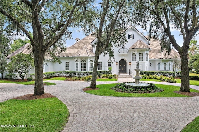 24736 Harbour View Dr, Ponte Vedra Beach, FL 32082 - mediterranean / spanish-style house with curved driveway, stucco siding, a front lawn, and a tiled roof