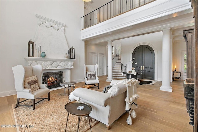 24736 Harbour View Dr, Ponte Vedra Beach, FL 32082 - living area with decorative columns, arched walkways, a warm lit fireplace, wood finished floors, and a high ceiling
