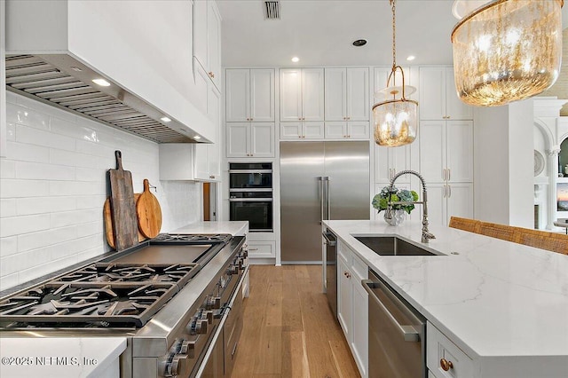 24736 Harbour View Dr, Ponte Vedra Beach, FL 32082 - kitchen featuring high end appliances, custom range hood, light wood-style flooring, white cabinets, and tasteful backsplash